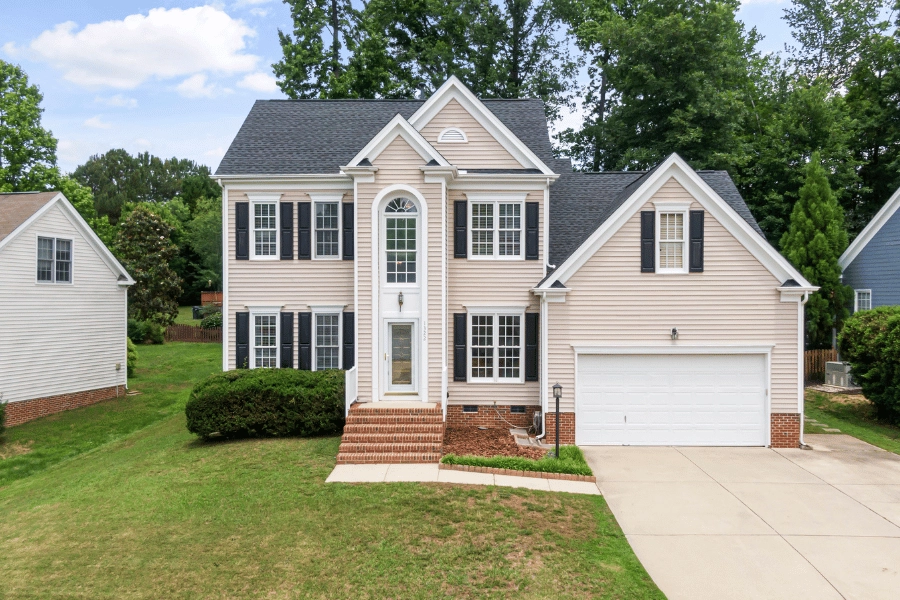 large single-family home in a suburban neighborhood with black shutters and large front yard with driveway
